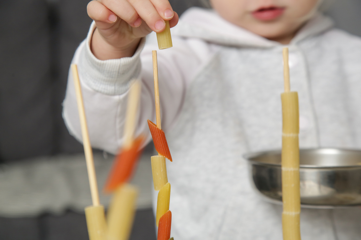 Fine motor pasta threading activity for kids. An easy and fun tower building challenge that works on fine motor skills as well as hand eye coordination.
