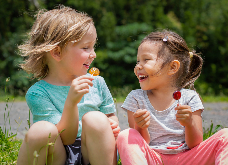 Kids playing outside eating lollipops. Best friends.